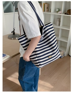 Gros plan du sac cabas en toile à rayures bleues et blanches avec plaque Handmade dorée