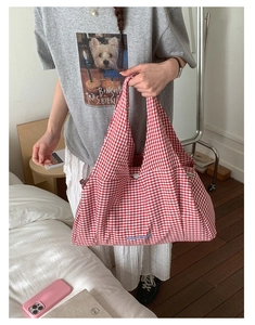 Detail of red checkered tote bag with blue side embroidery and zip pocket