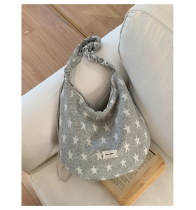 Detail of grey star print tote bag with a ruffled strap on a white sofa setting