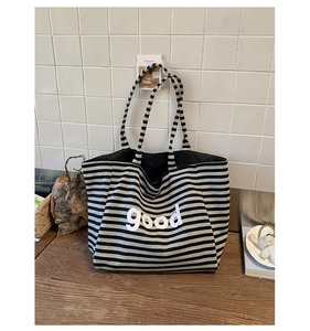 Close-up of black and white striped canvas tote bag with good letter print on wood
