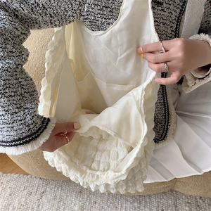 Detail view of the soft quilted texture and internal storage pocket of the cream tote bag