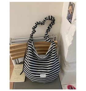 Detailed shot of striped tote bag featuring trendy ruffled strap and brand label