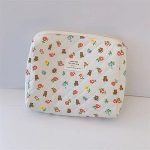 Detailed view of white quilted cotton cosmetic bag with bear and floral prints