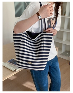 Gros plan d'un sac cabas en toile à rayures bleues et blanches avec plaque en métal