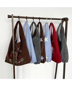 Detail view of colorful wool felt tote bags with embroidered patterns hanging on a rack