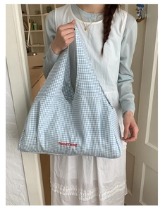 Detail of blue gingham tote bag with red GoodThing embroidery in a home setting