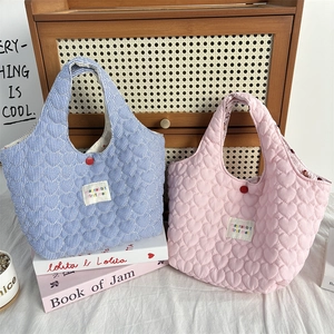 Detail of quilted tote bags featuring blue stripes and pink heart patterns with red buttons