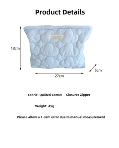 Detail view of light blue quilted cosmetic bag with dimensions 27x18x5cm and zipper closure