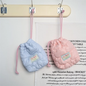 Close-up of heart-quilted drawstring storage bags in sky blue and soft pink colors