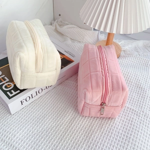 Detailed view of quilted plush cosmetic bags in cream white and soft pink colors