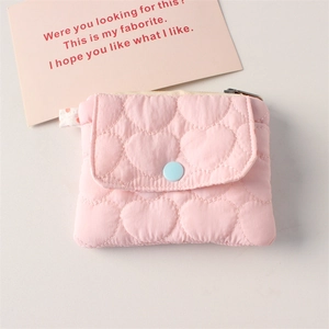 Detailed macro view of quilted heart pattern and blue snap button on pink mini wallet