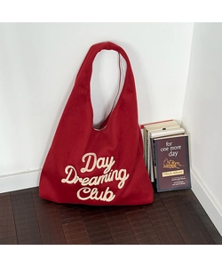 Macro view of a red wool tote bag featuring white Day Dreaming Club towel embroidery