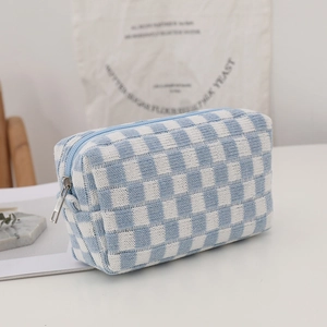 Blue and white checkered knitted cosmetic bag with silver zipper in a minimalist setting