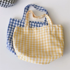 Detail of checkered canvas tote bags in vibrant yellow and blue with sturdy handles