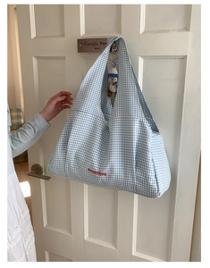 Detail of blue plaid tote bag with red embroidery and cute penguin plush charm