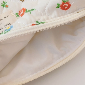Close-up of quilted floral cosmetic bag featuring a smooth nylon zipper and cotton lining