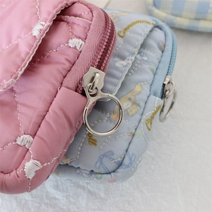 Détail macro du tissu matelassé cœur et du zip métallique sur une pochette Cinnamoroll