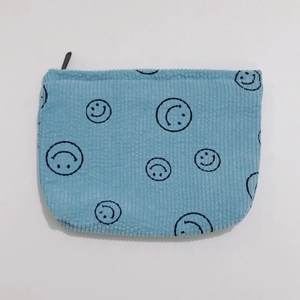 Macro detail of light blue corduroy fabric with black smiley faces and black zipper closure