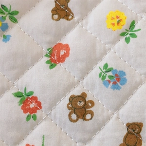 Detail of floral and bear print on quilted cotton fabric with diamond stitching texture