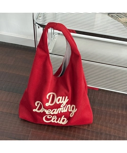 Detail of red wool hobo bag featuring white Day Dreaming Club embroidery and soft felt texture