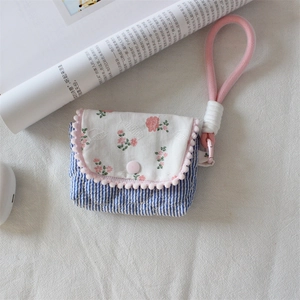 Close-up of floral fabric storage case with blue stripes and pink pom pom trim for cameras