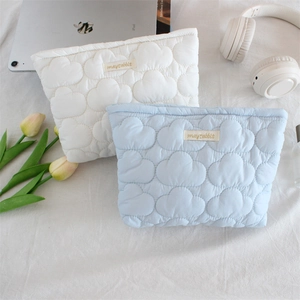 Quilted cloud texture makeup bags in white and blue shown in a lifestyle desktop setting