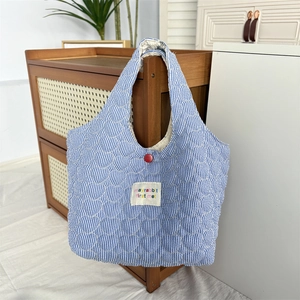 Detail of blue striped quilted heart tote bag with red button and mayrabbit logo patch