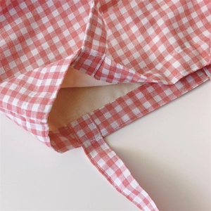 Detailed close-up of red and white checkered canvas tote bag with inner beige lining