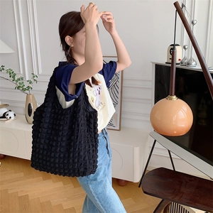 Lifestyle shot of a black bubble texture tote bag worn over the shoulder by a model