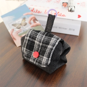 Close-up of mini checkered flannel and denim storage bag with red button on wood table