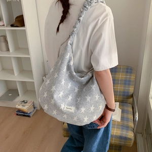 Striped hobo bag with star patterns and ruffled strap shown in a home setting