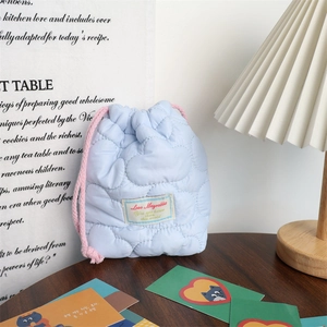 Detail of light blue quilted drawstring bag with cloud texture and pink cord closure