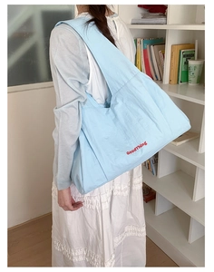 Close-up of a light blue nylon tote bag with red GoodThing print and wide shoulder strap