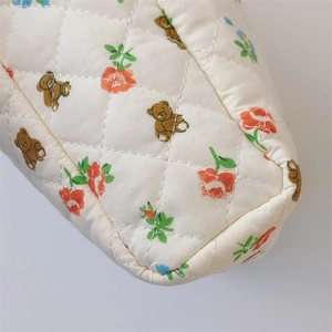Close-up of quilted floral cotton fabric with brown bear pattern and rhombus texture