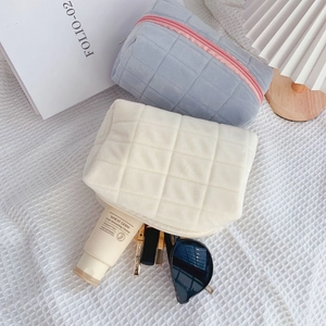 Quilted cosmetic bags in blue and beige with square pattern and zipper detail