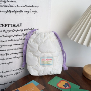 Detail of white quilted drawstring pouch with purple cord and padded bubble texture