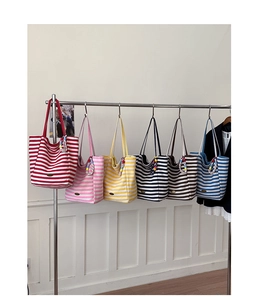Détail de sacs cabas en toile rayée avec des breloques décoratives sur un présentoir