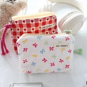 Detail of fabric bow coin pouches with MAY RABBIT labels and colorful braided zipper pulls