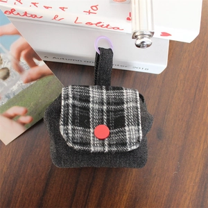 Close-up of stylish mini storage bag with denim texture and plaid flap detail