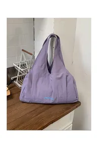 Detailed view of the purple textured tote bag showing wide straps and front lettering