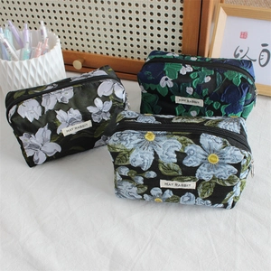 Close-up of floral jacquard pouches in black, blue, and teal with MAY RABBIT label
