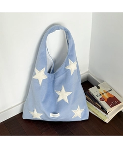 Close-up of light blue wool tote bag featuring white star patterns and brand label