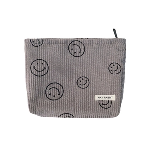 Gray corduroy cosmetic bag featuring black smiley face prints and a top zipper closure
