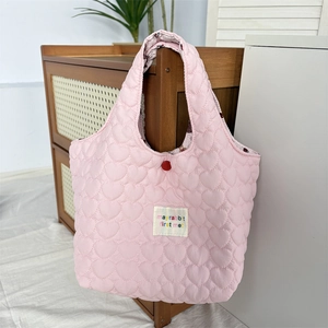 Close-up of pink quilted tote bag with heart patterns and mayrabbit brand tag