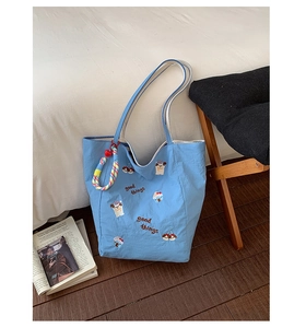 Détail du sac cabas en toile bleue avec broderie chien et breloque tissée colorée