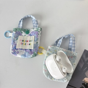 Détail de la pochette pour écouteurs en tissu floral avec bouton et dragonne à carreaux