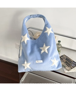 Macro view of light blue plush tote bag with white star patches and soft furry texture
