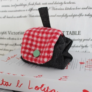 Detailed shot of mini storage pouch featuring red gingham flap and green button accent