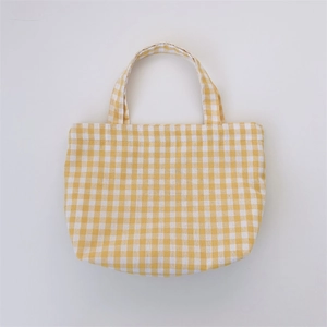 Detail view of yellow plaid canvas lunch bag with soft texture and curved base design