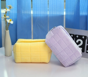 Detail of quilted plush pencil cases in purple and yellow with silver zippers